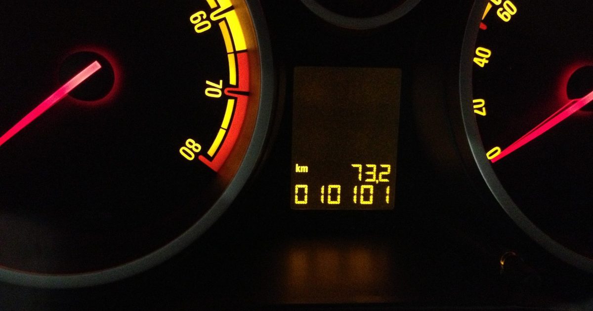 Close-up of a car dashboard at night with red needles and glowing amber speedometer and tachometer dials