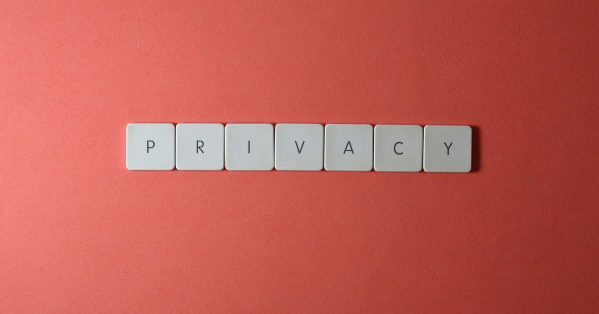 White keyboard key tiles spelling the word privacy, laid out in a row on a coral red background