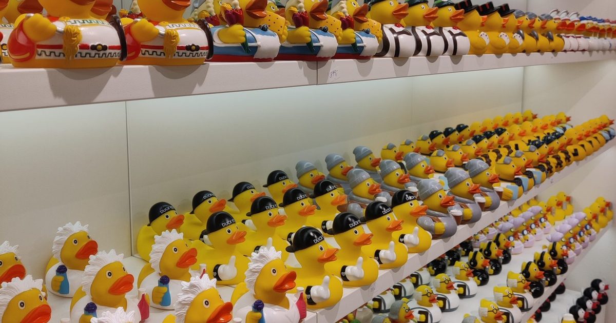 Long white shelves packed with hundreds of rubber ducks in different costumes, rows repeating into the distance