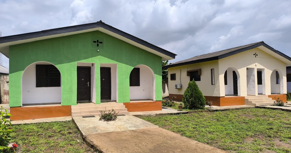 Two single-story houses side by side with the same arched porch design, one painted bright green and the other cream with orange trim