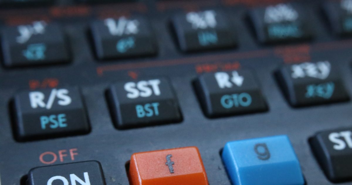 Close-up of black calculator keys with white and teal labels, an orange f key and a blue g key in the bottom row