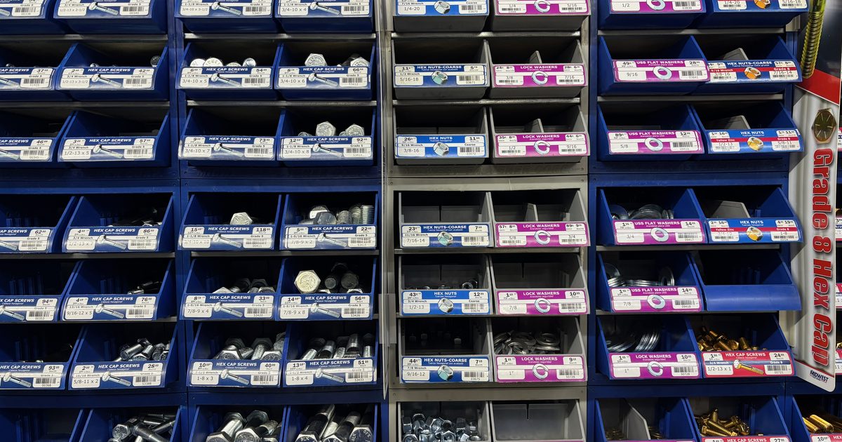 A wall of blue and grey bins in a hardware store, each labelled and filled with nuts, bolts and washers sorted by size