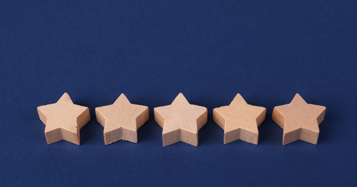 Five wooden star shapes lined up in a row on a dark blue background, like a five-star rating